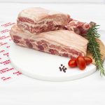 Costilla de cerdo en plato con hierbas, lista para parrilla u horno – Cortes & Brasas